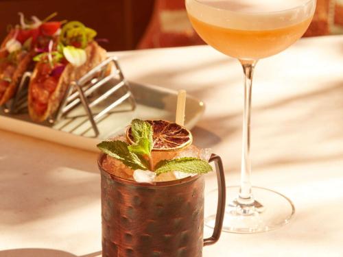 a drink on a table next to a plate of food at Mondrian Bordeaux Les Carmes in Bordeaux