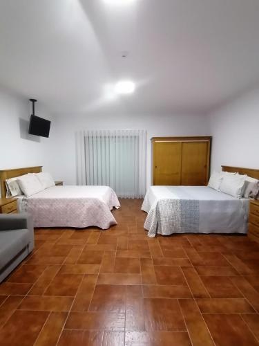 two beds in a room with wooden floors at Hostel Encostas Do Douro in Marco de Canaveses