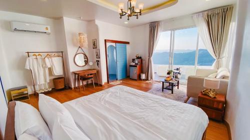 a bedroom with a white bed and a large window at Nontawa Villa & Cafe in Ban Huai Khai