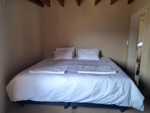 1 cama blanca grande con sábanas y almohadas blancas en Liphofung Cave, Chalets en Butha-Buthe
