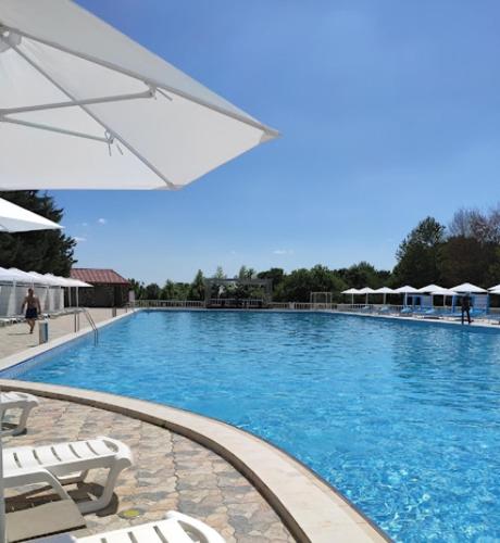 a large swimming pool with chairs and an umbrella at Xəzər İstirahət Mərkəzi in Bunud