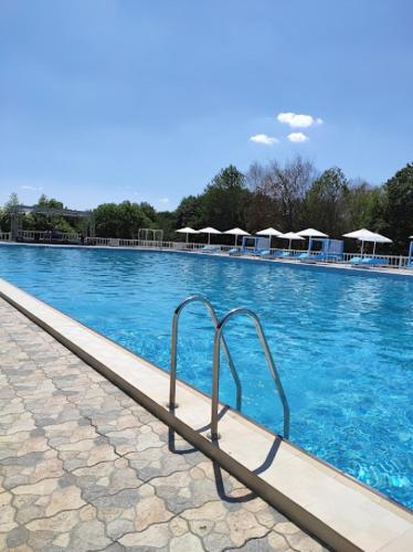 a swimming pool with blue water and tables and umbrellas at Xəzər İstirahət Mərkəzi in Bunud