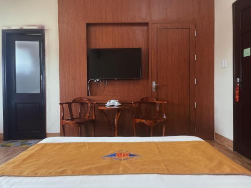 Ðông Hà的住宿－Khách sạn HOÀ BÌNH QUẢNG TRỊ，一间卧室配有一张带桌子的床铺和一台平面电视。