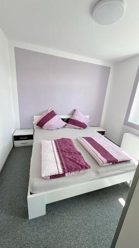 a white bed with pink and white sheets and pillows at Berzi Ferienwohnung 2 Görlitz in Görlitz