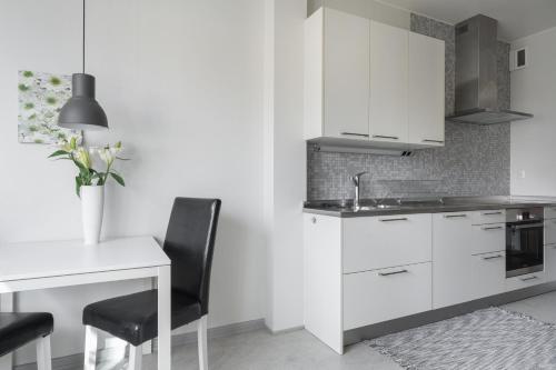 una cucina con armadi bianchi, tavolo e lavandino di Live and Stay Lagerbring a Göteborg