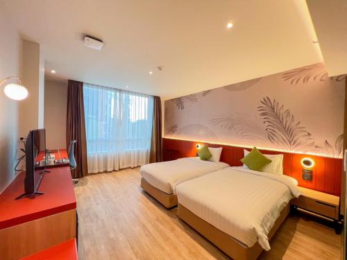 a hotel room with two beds and a television at Buri Sriphu Hotel & Convention Centre in Hat Yai