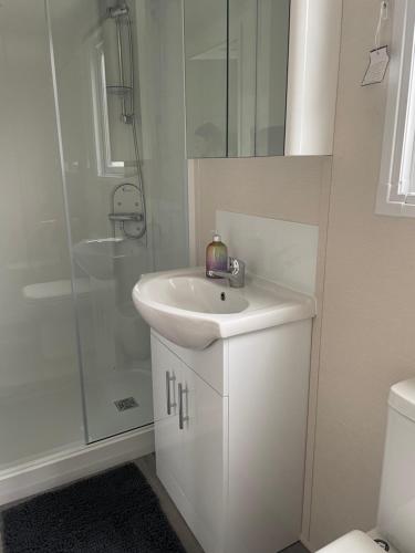 a white bathroom with a sink and a shower at 26 Sherwood, South Lakeland Leisure Village in Carnforth
