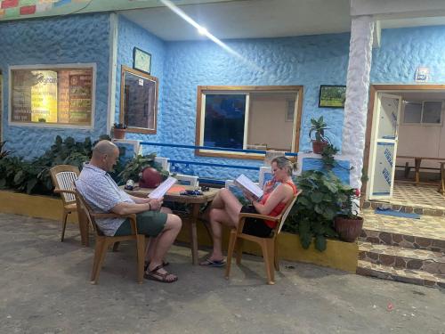 a couple of people sitting at a table with books at Hong Qi Hotel in Chitwan