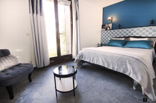 een slaapkamer met een bed, een bank en een tafel bij Maison des Soupirs in Montpon-Ménestérol
