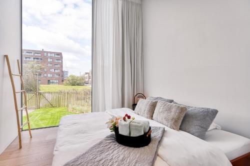 een woonkamer met een bank en een groot raam bij Aimé aan zee, villa te Oostende - Oosteroever met 2 parkeerplaatsen in Oostende