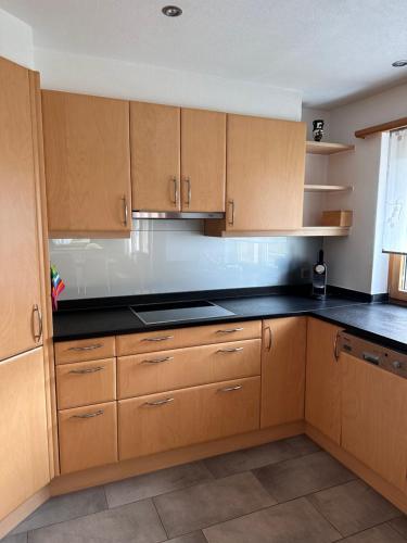 a kitchen with wooden cabinets and black counter tops at Ferienwohnung Crameri in Klosters