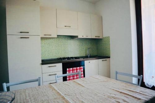 una cocina con armarios blancos y una mesa con sillas. en Appartamento Paradise, en Borgo Ticino