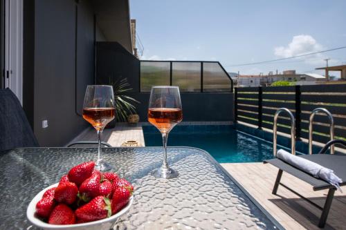 two glasses of wine and a bowl of strawberries on a table at 7thHeaven Luxury aprts in Chania Town