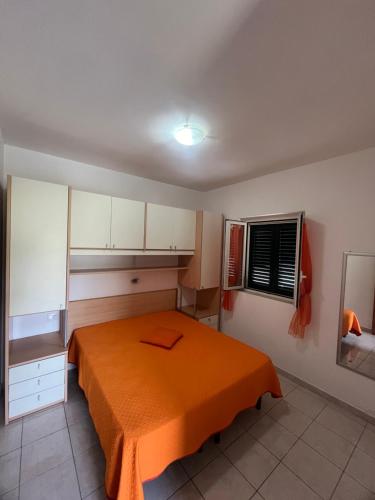 1 dormitorio con 1 cama con manta naranja en Villa Angela case vacanza, en Vieste