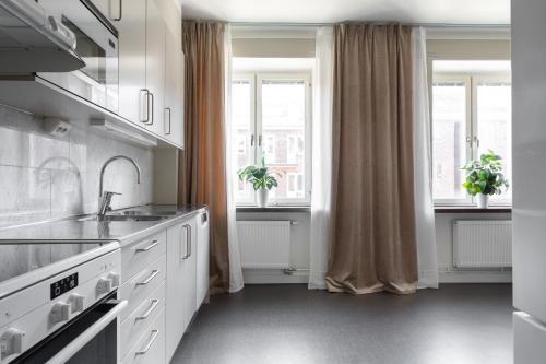 a kitchen with white cabinets and windows and a sink at Live and Stay VR40 in Gothenburg