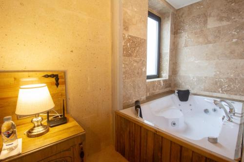 a bathroom with a tub with a lamp and a window at Milagro of Cappadocia in Uchisar