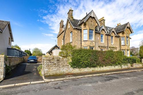 a large house with a car parked in front of it at Lower Tweedknowe - ground floor villa Melrose in Melrose