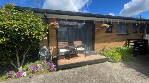 a house with two chairs and a porch with flowers at Mels Retreat in Te Kuiti