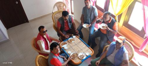 Eine Gruppe von Menschen, die an einem Tisch sitzen und Essen essen. in der Unterkunft Hotel Abhinav Jaisalmer in Jaisalmer