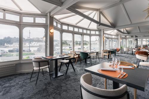 un restaurante con mesas, sillas y ventanas en Logis hôtel restaurant Le Goyen, en Audierne