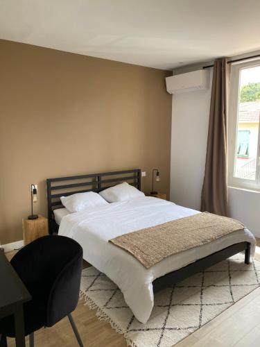 a bedroom with a bed and a chair and a window at Appartement La Maouin 2 pièces in Saint-Laurent-du-Var