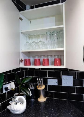 a kitchen cabinet filled with glasses and bottles at 4 Bed complete Home in Edinburgh Near Airport in Edinburgh