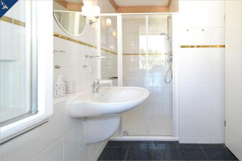 La salle de bains blanche est pourvue d'un lavabo et d'une douche. dans l'établissement Studio, à Ahlbeck