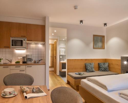 a kitchen and a bedroom with a bed and a table at Ferienhof Neusacher Moser in Weissensee