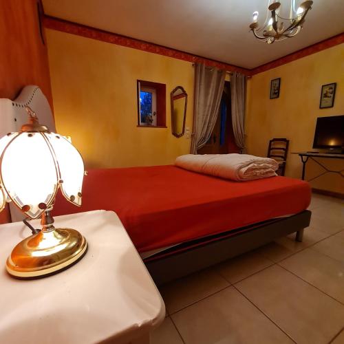 une chambre avec un lit et une lampe sur une table dans l'établissement Impérial, à Puy-lʼÉvêque
