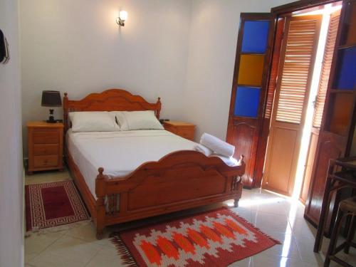 um quarto com uma grande cama de madeira e uma janela em Casa Mogador em Essaouira