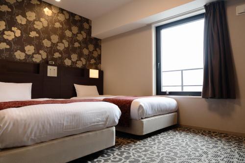 a hotel room with two beds and a window at Hotel. Links Namba in Osaka