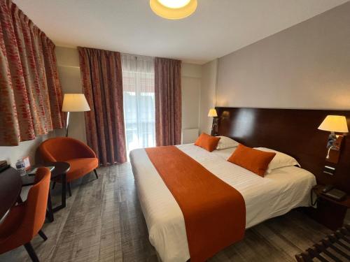 リボーヴィレにあるオテル ル メネストレルの大きなベッドとデスクが備わるホテルルームです。