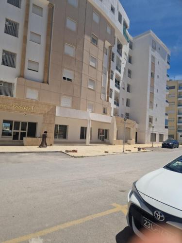 un coche aparcado en un aparcamiento frente a un edificio en Appartement proche de la plage à 200 M restaurant Piccolino en Dar el Koudia