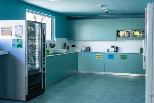 a kitchen with blue cabinets and a refrigerator at The Boc Hostels - Beach in Can Pastilla