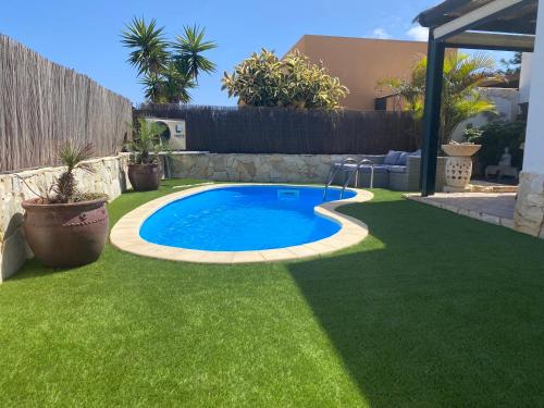 a swimming pool in a yard with green grass at Casa Rosalía in Corralejo