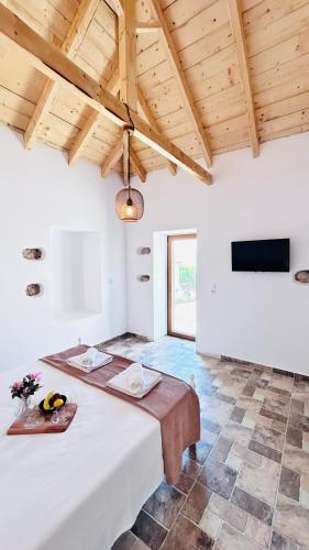 a large white room with a table and a television at Cassiopea Guest House Evia Greece in Nerotriviá