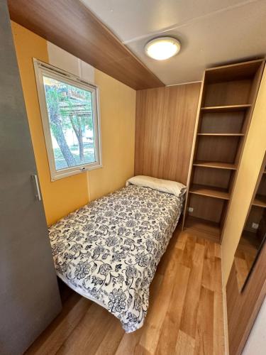 a small bedroom with a bed and a window at Bungalow BAMBOLERA in Torrelaguna