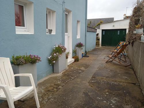 une maison bleue avec des chaises blanches dans une cour dans l'établissement Chez Fa et Pascal, à Lanester