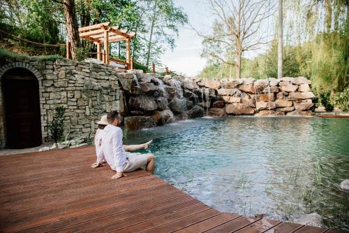a woman sitting on a wooden deck next to a swimming pool at Penzion U Zběhlíka in Svitavy