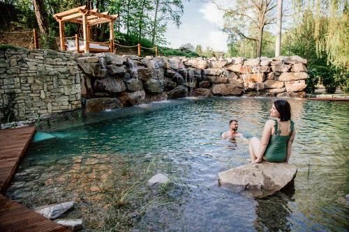 a man and a woman sitting on a rock in a pool at Penzion U Zběhlíka in Svitavy