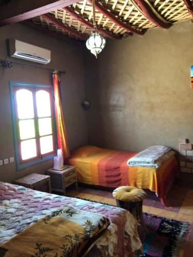 a bedroom with two beds and a window at GITE LA GROTTE VALLEE in Aoûtouss