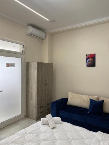 a bedroom with a bed and a blue couch at Troy ApartHotel Durres in Durrës