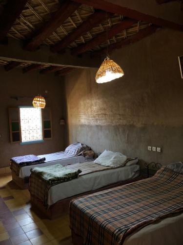 a bedroom with two beds and two chandeliers at GITE LA GROTTE VALLEE in Aoûtouss
