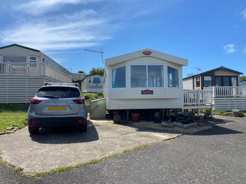 a small car parked in front of a tiny house at Stunning Caravan on Swanage Bay View Holiday Park in Swanage