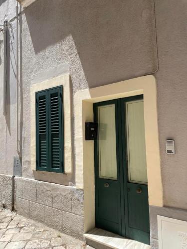 a building with a green door and two windows at Dimora Chialù in Soleto