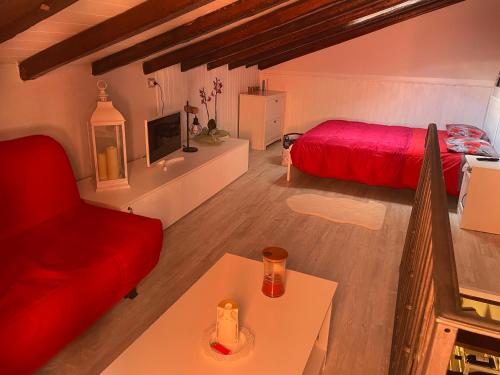 a living room with a red bed and a table at La dolce dimora in Chioggia