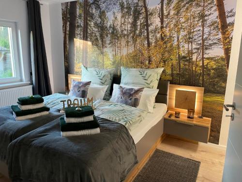 a bedroom with two beds and a large mural of trees at Wellness Ferienhaus Bergheide in Michendorf