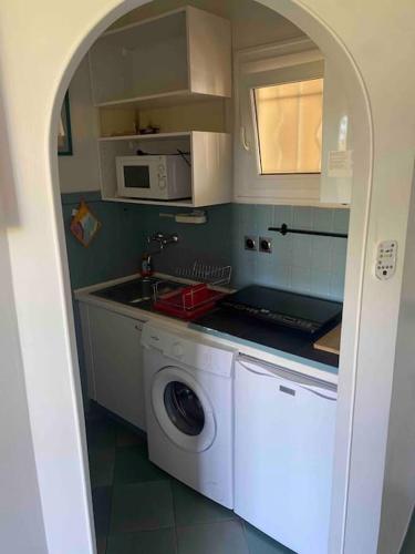 une cuisine avec un lave-linge et un micro-ondes dans l'établissement Studio bord de mer Saint Rahael, à Saint-Raphaël