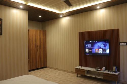Habitación con TV de pantalla plana en la pared en AVTARA RESORT RISHIKESH, en Rishīkesh