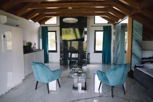 salon z 2 niebieskimi krzesłami i stołem w obiekcie Casa moderna in Sinteu - intersectia intre modern si linistea naturii w mieście Huta Voivozi
